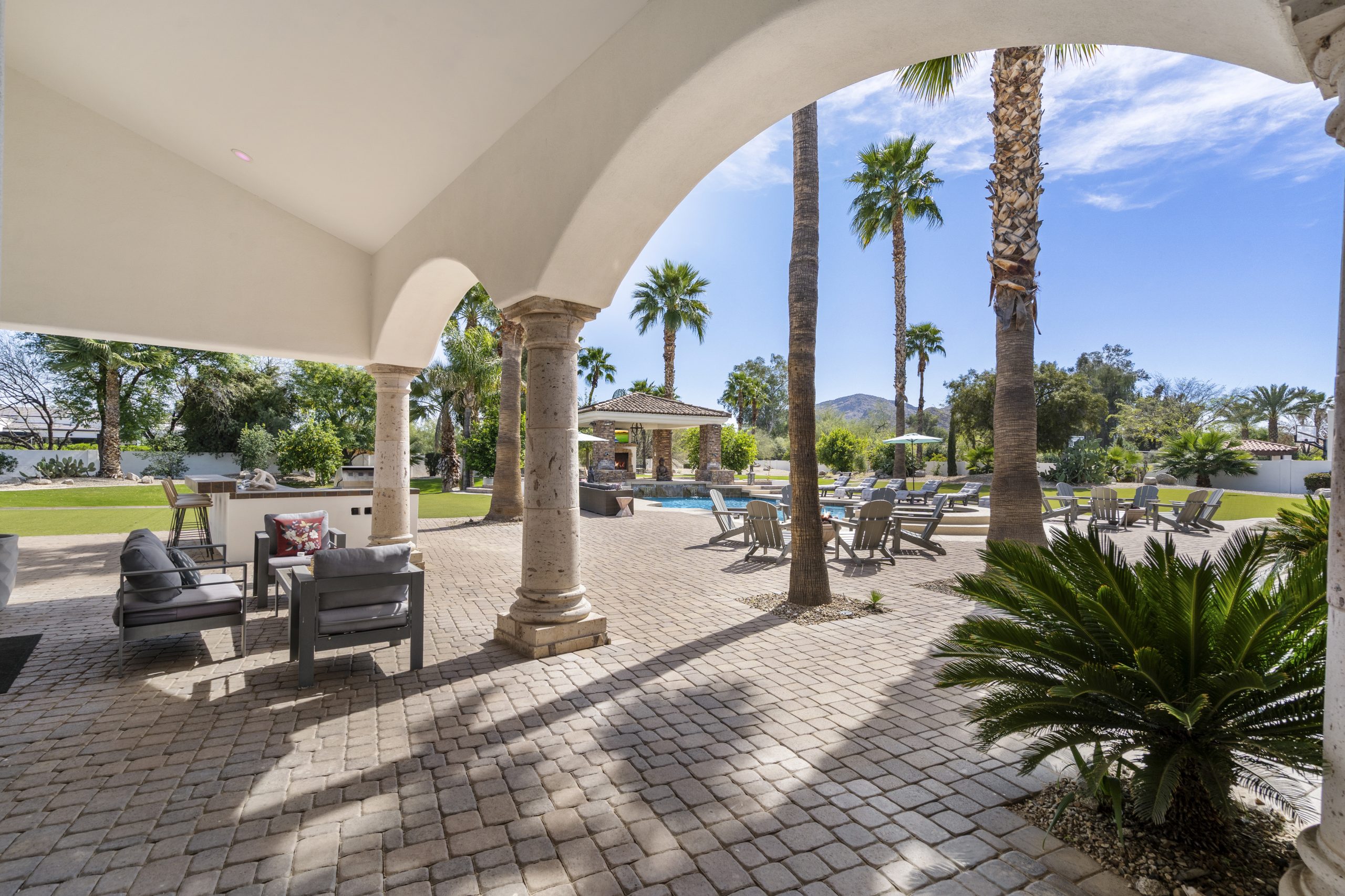 Silverleaf, Scottsdale: stone-columned covered patio arch overlooking a backyard pool and mature palm trees